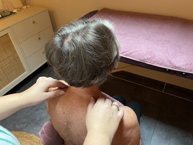 Sanftes streichen bei der MANNEA-Behandlung mit Anja Wagner Anja Wagner streicht sanft den Rücken einer Kundin im Sitzen bei Durch die Blume.“