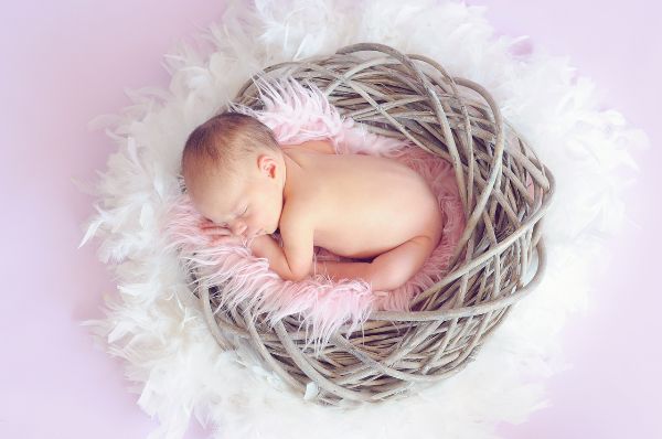 Schlafendes Baby – Ein Bild der Ruhe und Geborgenheit Symbolbild eines entspannten, schlafenden Babys in einem kuscheligen Nest, das die Harmonie und Sicherheit der frühen Kindheit verkörpert.